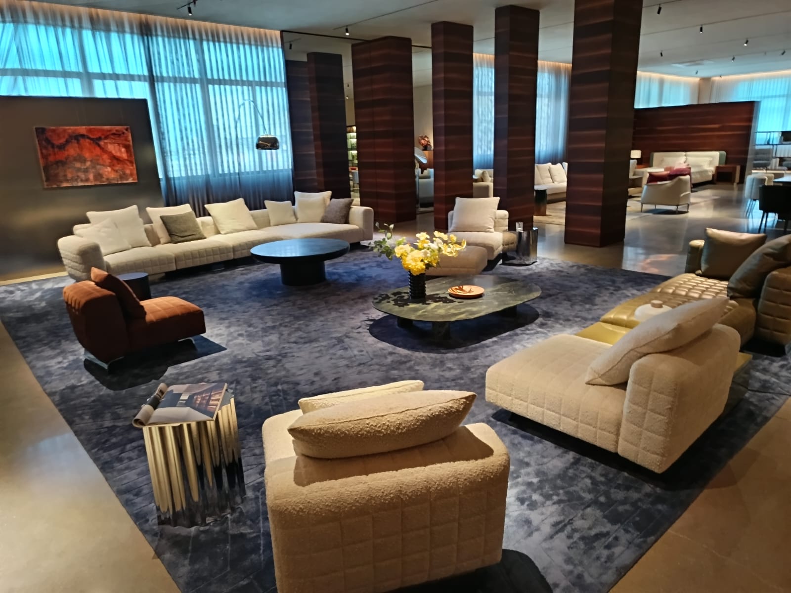 Prostoren hotelski sprejemni salon s kremnimi sedežnimi garniturami, fotelji in lesenimi stebri